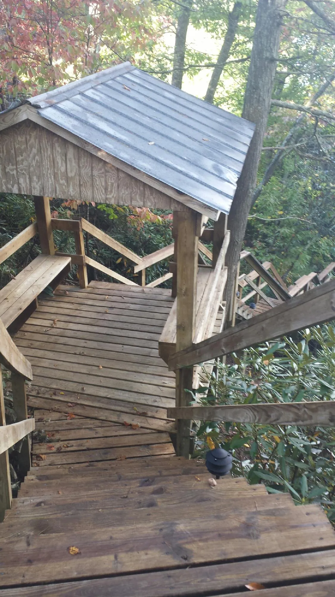 Metal roofed shelter over wooden steps on a wooded walkway — Skylight Repair & Installation work by our crew in Brookside