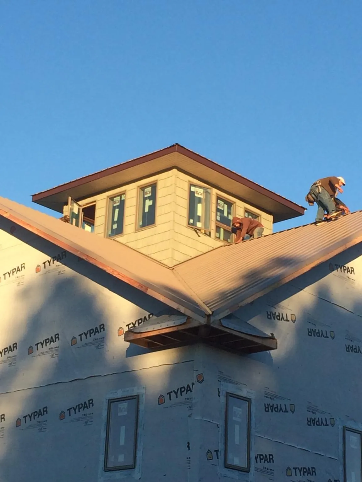 Roofers working around a rooftop cupola on a new metal roof at sunset — Roof Waterproofing in Brookside by Roofing Brothers
